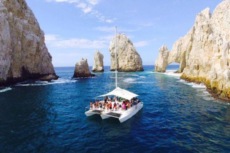 42-foot sailing trimaran with guests on deck beside the rock pinnacles of El Arco
