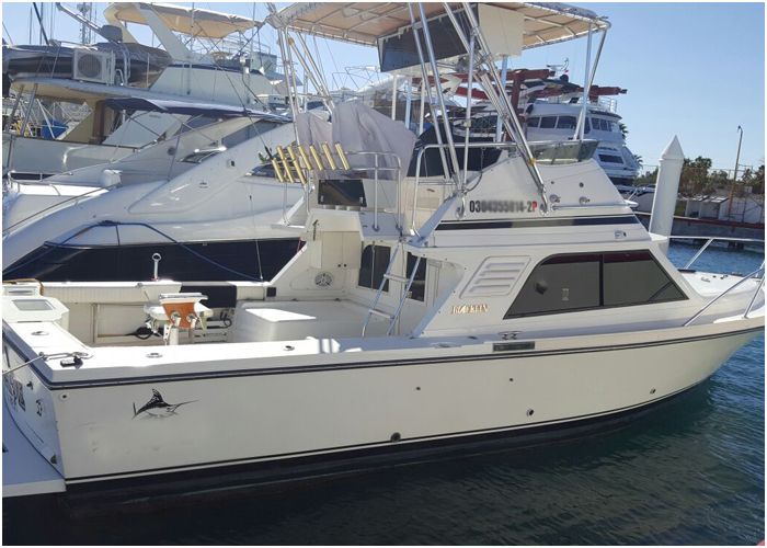 White sportfishing boat with a tuna tower tied up at the dock