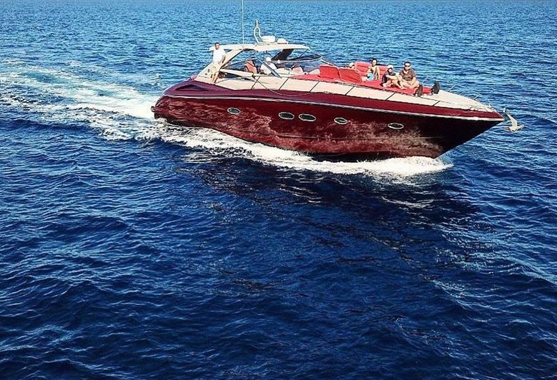 Red 58-foot Sunseeker sport yacht cruising on open water