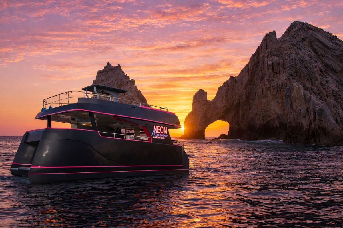 Catamaran at sunset with the sky glowing orange through El Arco