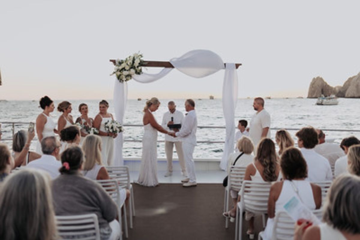 Wedding ceremony on the deck of an event catamaran with Land's End in the background
