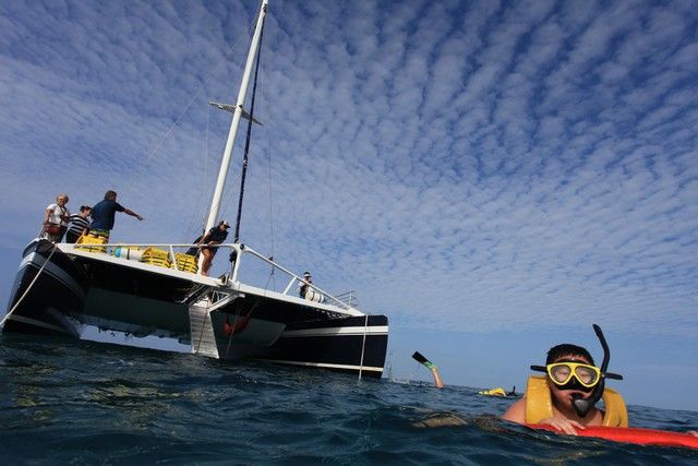 Snorkeler in the water beside a catamaran at anchor