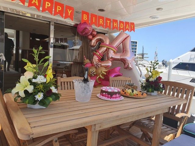 Happy Birthday banner, balloons and flowers set up on the aft deck of a yacht