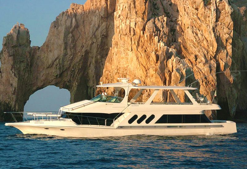 72-foot Bluewater yacht cruising in front of El Arco in golden light